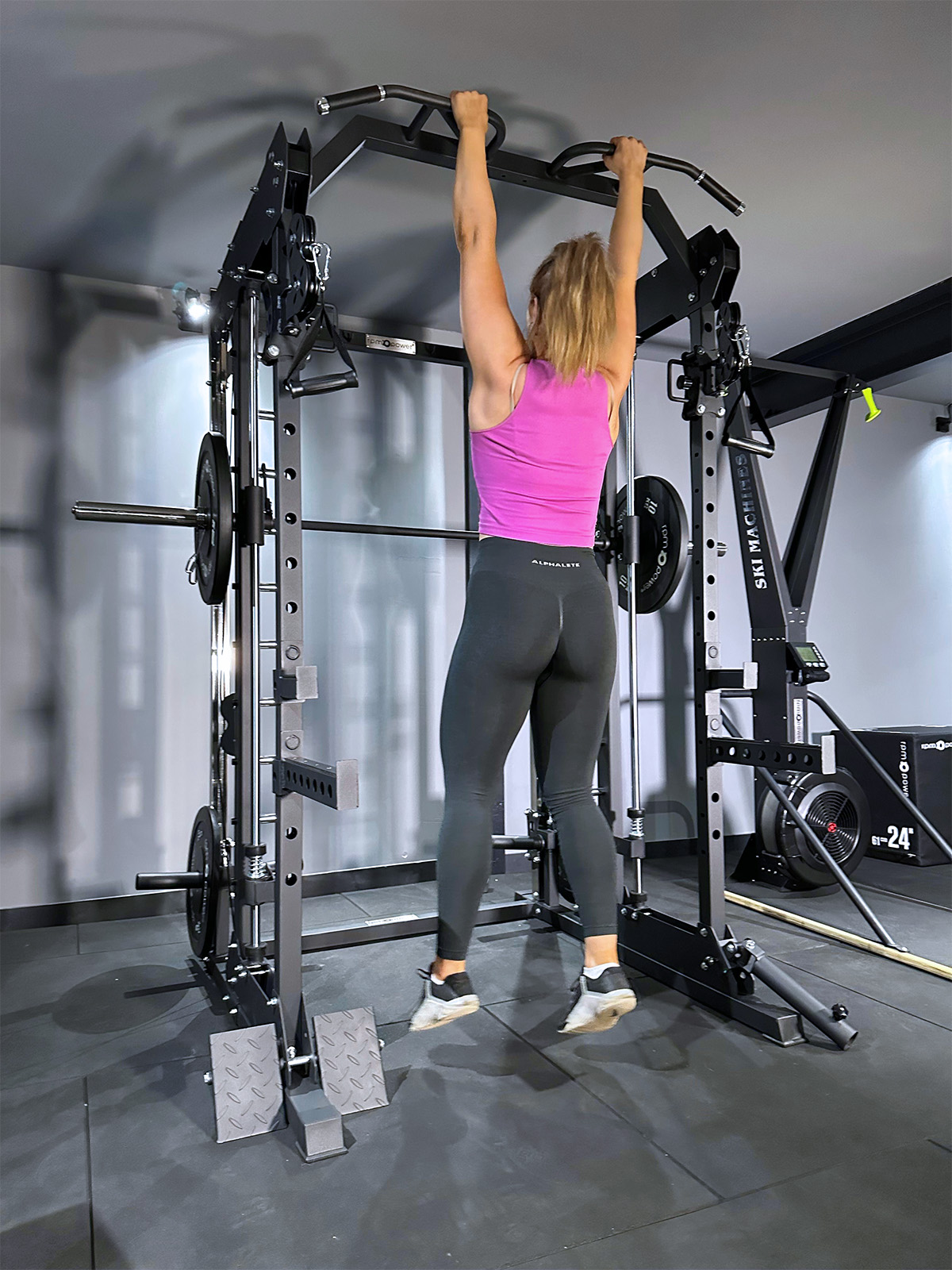 Woman doing pull ups row on home gym power rack
